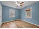 Bright bedroom features two windows, hardwood floors, and blue painted walls at 582 Pollyanna Rd, Henderson, NC 27537