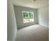 A cozy bedroom featuring neutral carpet and trim and a large window overlooking the lawn at 60 Valebrook Ct, Youngsville, NC 27596