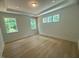 Bright bedroom featuring tray ceilings, large windows, and hardwood floors at 60 Valebrook Ct, Youngsville, NC 27596
