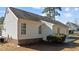 Backyard of house features a lawn, mature shrubbery, and brick-lined foundation with white siding at 613 Flaherty Ave, Wake Forest, NC 27587