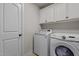 Well-lit laundry room with white cabinets, washing machine, and dryer at 690 Hawthorne Pl, Creedmoor, NC 27522