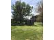 Wide shot of backyard featuring a shed, framed by large trees and green grass at 8510 Polaris Dr, Bahama, NC 27503