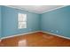 A bright bedroom features hard wood flooring and a window with blinds at 904 Churchill Glen Blvd, Knightdale, NC 27545