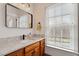 Bathroom boasts wood cabinets, white countertops, black fixtures, and a bright window at 907 Vintage Hill Pkwy, Durham, NC 27712