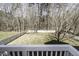 View of the tree-lined backyard from the white deck railing at 9244 Palm Bay Cir, Raleigh, NC 27617