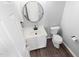 Small powder room with a toilet, sink, white cabinets, and a round mirror at 1204 Matthews Glen Dr, Knightdale, NC 27545