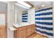 Bathroom showcasing a double sink vanity with wood cabinets and a blue and white striped shower curtain at 12808 Old Stage Rd, Willow Springs, NC 27592