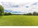 Expansive grassy field with scattered trees under a partly cloudy sky at 149 Bonica Creek Dr, Garner, NC 27529