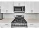 Close up of a stainless steel range and microwave with white cabinets and subway tile backsplash at 1723 Starlit Sky Ln, Cary, NC 27519