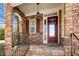 Close-up of a welcoming front door with sidelight and decorative hardware set in a stone archway at 1800 Pierre Pl, Apex, NC 27502