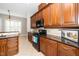 Well-lit kitchen features dark granite countertops, wood cabinets, and modern appliances at 1800 Pierre Pl, Apex, NC 27502