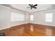 Spacious main bedroom with hardwood floors, a ceiling fan, and three windows at 1800 Pierre Pl, Apex, NC 27502