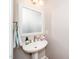 Well-kept powder room featuring a pedestal sink, decorative mirror and fresh flowers at 1800 Pierre Pl, Apex, NC 27502