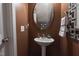 Cozy powder room featuring a pedestal sink, stylish mirror, and warm brown walls at 207 Kinnakeet Dr, Durham, NC 27704