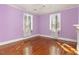 Charming bedroom featuring hardwood floors, soft purple walls, and natural light from two windows at 2110 Cokey Rd, Rocky Mount, NC 27801