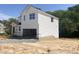 Side view of a two-story home featuring a white exterior, visible foundation, and an attached unfinished two-car garage at 212 Fast Pitch Ln, Four Oaks, NC 27524