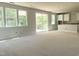 Spacious living area with large windows and sliding glass doors, connected to an unfinished kitchen space at 212 Fast Pitch Ln, Four Oaks, NC 27524