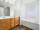 Bright bathroom featuring dual sinks, wood cabinets, and a separate tub at 2574 Primrose Ln, Creedmoor, NC 27522