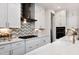 Bright, modern kitchen featuring white cabinetry, stainless steel appliances, and chic backsplash at 292 Choice Trl, Pittsboro, NC 27312