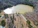 Aerial view of a large pond surrounded by a gravel drive and mature trees on the property at 292 Choice Trl, Pittsboro, NC 27312