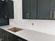 A closeup of the gray countertops, stylish backsplash, dark cabinets, and gold hardware in this new kitchen at 3291 Roundly Rd # 14, New Hill, NC 27562