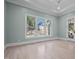 Light-filled bedroom featuring hardwood floors, large windows, and tray ceiling at 3513 Eden Croft Dr, Raleigh, NC 27612