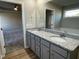 Bathroom featuring a double sink vanity with granite countertops, a large mirror, and views into the main bedroom at 39 Flatland Dr, Princeton, NC 27569