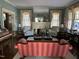 Bright living room with a white fireplace, large windows with sheers, vintage sofa, and hardwood floors at 405 N Massey St, Selma, NC 27576