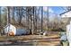 View of the spacious back yard with storage building and mature trees at 4775 Barber Mill Rd, Clayton, NC 27520