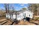 View of a one story home with a white exterior, green door, and patio furniture in a wooded area at 4775 Barber Mill Rd, Clayton, NC 27520