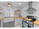 Close-up of a bright kitchen featuring stainless steel appliances, a farmhouse sink, and butcher block countertops at 4775 Barber Mill Rd, Clayton, NC 27520