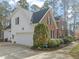 Exterior showcasing a brick and white home with a two-car garage and manicured landscaping at 5032 Big Creek Rd, Raleigh, NC 27613