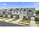 View of new construction townhomes with brick accents and manicured lawns on a sunny day at 64 Lavender Ln # 153, Clayton, NC 27520