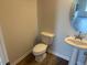 Powder room with toilet, pedestal sink, and a modern round mirror at 72 E Victory View Ter, Smithfield, NC 27577