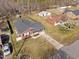 Aerial view showing the brick home with a fenced yard, driveway, and mature trees in the neighborhood at 74 Azalea Dr, Roxboro, NC 27573
