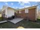 Back exterior featuring a brick facade, small patio, grill, and a mix of siding and brick accents at 74 Azalea Dr, Roxboro, NC 27573
