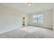 Neutral main bedroom with tray ceiling, large window, and ensuite bathroom access at 936 Jasper Mine Trl, Raleigh, NC 27610