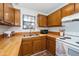 Galley kitchen featuring wood cabinets, wood counters, stainless steel sink, and standard white appliances at 100 Forsyth Dr, Chapel Hill, NC 27517