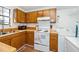 Functional kitchen with wood cabinets, basic appliances, and a sink near a window, plus a nearby washer and dryer at 100 Forsyth Dr, Chapel Hill, NC 27517