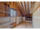 Unfinished attic space with exposed wood beams, a window, and metal shelving for storage at 1017 Holly Creek Ln, Chapel Hill, NC 27516