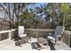 Outdoor deck featuring two cushioned chairs, two wicker tables, and a private wooded backdrop for relaxation at 1017 Holly Creek Ln, Chapel Hill, NC 27516