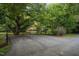 View of a home's paved driveway with mature trees and a wooden fence in a landscaped yard at 1017 Holly Creek Ln, Chapel Hill, NC 27516