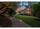 A brick house at dusk with a walkway and lighted landscape with a covered porch at 1017 Holly Creek Ln, Chapel Hill, NC 27516