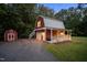Garage with an apartment above featuring a metal roof, a porch, and a small storage shed at 1017 Holly Creek Ln, Chapel Hill, NC 27516