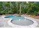 Stunning freeform pool with stone decking, waterfall, and integrated spa, surrounded by lush greenery at 1017 Holly Creek Ln, Chapel Hill, NC 27516