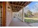 Covered porch with brick columns and wood flooring, with a backyard view and exterior light at 1017 Holly Creek Ln, Chapel Hill, NC 27516
