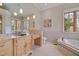 Elegant bathroom with marble countertops, built-in vanity, soaking tub, and a large window offering natural light at 102 Anna Lake Ln, Cary, NC 27513