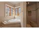 Well-lit bathroom features a soaking tub, walk-in shower, and multiple windows offering natural light and views at 102 Anna Lake Ln, Cary, NC 27513