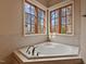 A corner tub with tile surround is lit by corner windows in this beautiful bathroom at 102 Anna Lake Ln, Cary, NC 27513
