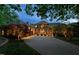 Grand estate features a circular driveway, stone facade, and well-manicured landscaping, illuminated for evening appeal at 102 Anna Lake Ln, Cary, NC 27513